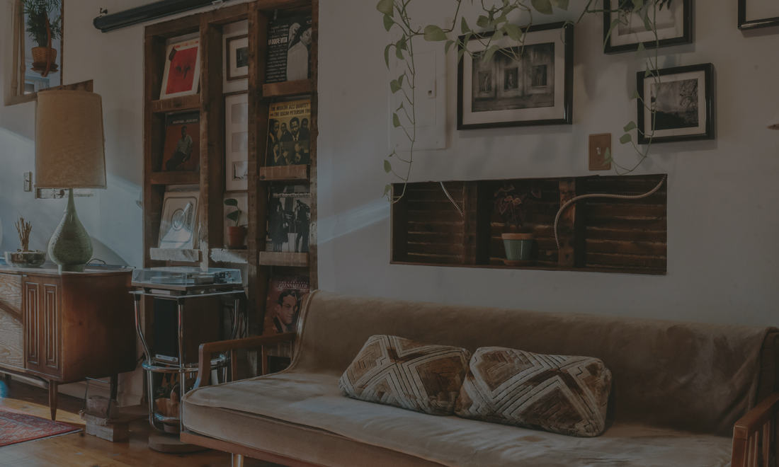 Moody quiet luxury living room with soft warm lighting, dark green tones, vintage décor, and an Ava + Bru candle styled on a textured table.